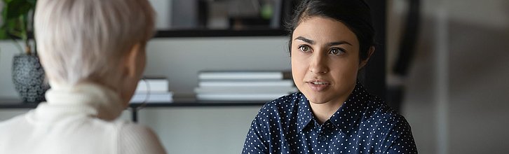 Zwei Frauen im Gespräch, eine ist nur von hinten zu sehen